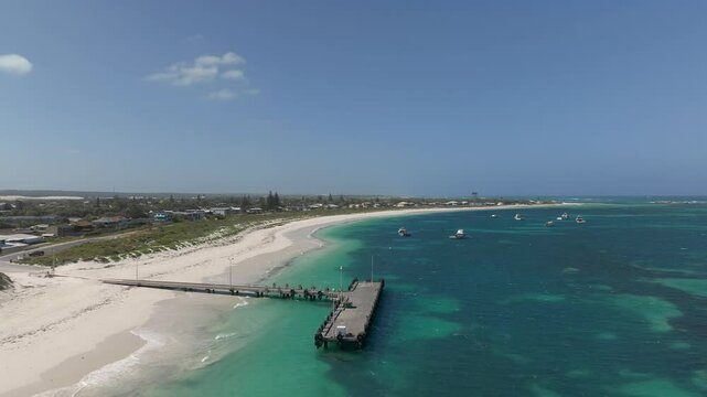 Flying backwards from above the jetty of a small coastal town then ascending to reveal more of the town.