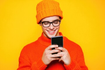 Fototapeta premium A person holding a cell phone and wearing an orange sweater, suitable for personal use or business illustration