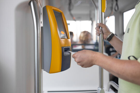 Traveler validating train ticket at terminal. Yellow ticket validation machine on a modern public transport bus. Modern prepaid public transport ticketing system with validation machine at entrance of