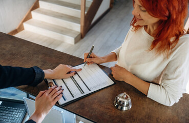 Registration process, document. Woman is at reception of the modern hotel