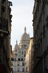 Street view of sacre coeur basilica in Montmartre in Paris in-between buildings in the sun