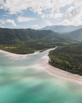 Aerial view of pristine beach and turquoise ocean surrounded by lush rainforest and mountains, Noah Creek, Daintree Rainforest, Queensland, Australia.