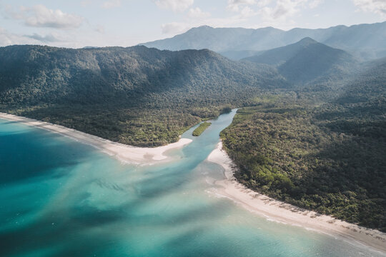 Aerial view of noah creek winding through the lush daintree rainforest and sandy beach, cape tribulation, queensland, australia.