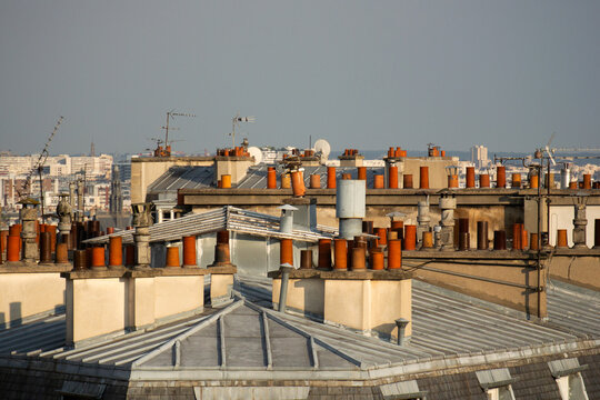 Roofs with orange chimneys in Paris in the sun and a grey sky, landscape view