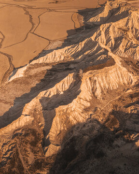 Aerial view of dramatic rock formations and arid desert landscape under warm tones, Mirador de Juan Obispo, Bardenas Reales, Navarre, Spain.