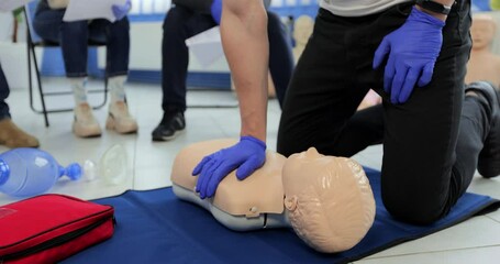 Close up man demonstrating CPR on teen mannequin in first aid class.