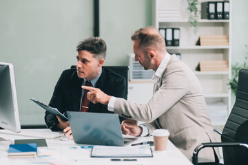 Two businessmen working together Analyze financial reports with charts and graphs while using the...