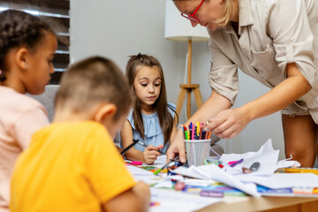 Children engaged in drawing at a classroom table.