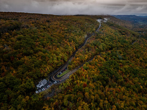 Aerial view of colorful autumn foliage and serene winding road through lush hills and forest, Clarksburg, United States.