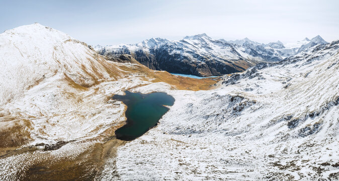 Aerial view of serene Lac des Autannes surrounded by majestic snow-capped mountains in winter, Grimentz, Switzerland.