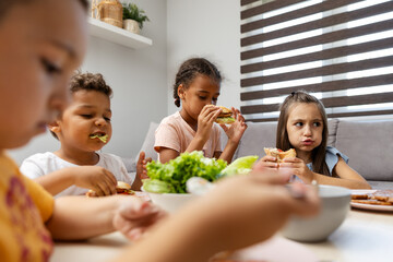 Children enjoying lunch with sandwiches and salad.