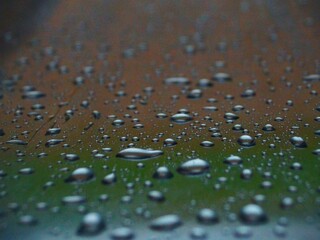 Raindrops on a slide reflecting orange and green.