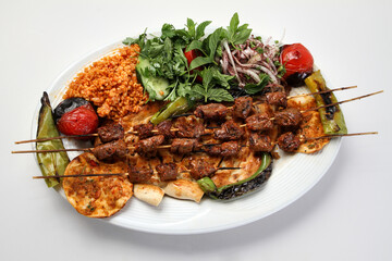 Turkish kebab lamb meat on skewer.
with vegetables and rice on a serving plate
