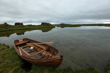 Small wooden boat on a calm lake water