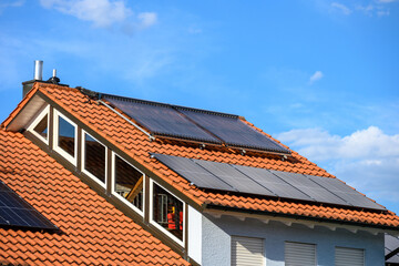 Nutzung der Sonnenenergie mit Solarthermieanlage und Solarzellen auf modernem Hausdach