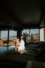 Fototapeta premium A young woman swims in an indoor pool with a view of the mountains. A woman enjoys relaxation in a spa. Relaxing near the pool. Hotel holiday concept 4k