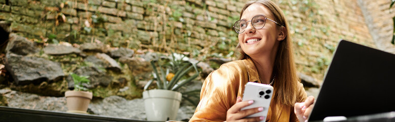 In a cozy cafe, a young woman smiles as she holding her phone, living life to the fullest.
