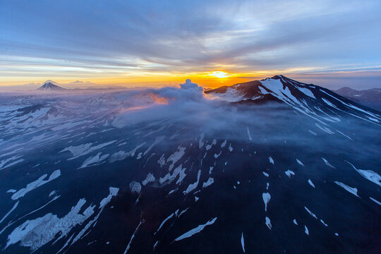 Aerial view of mutnovsky volcano at sunset with clouds and snow, kamchatka, russia.