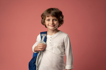 in a photo studio on a pink background stands a smiling boy of ten years old, a schoolboy in a...