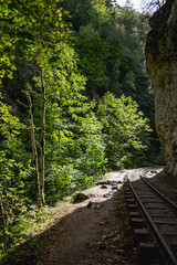 
A shelf of space was formed in the gorge and a railway was laid along it, along the rock. The sun enters the gorge and illuminates the rock ledge.