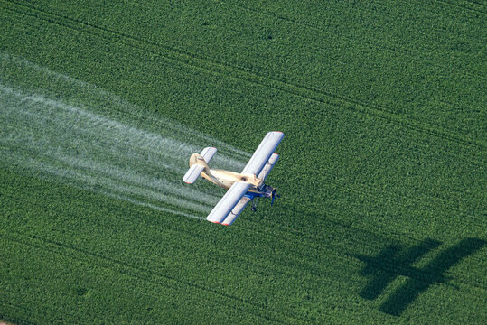 Aerial view of green farmland with tractor spraying crops in summer, Stavropol Krai, Russia.
