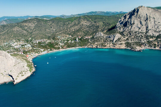 Aerial view of beautiful turquoise coastal bay surrounded by rugged mountains and serene beach, Novyi Svit, Crimea, Russia.