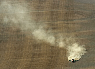 Aerial view of a cultivated agricultural field with a tractor stirring up dust, Stavropol Krai, Russia.