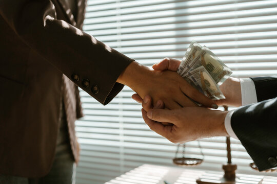 Businessman passing money to lawyer for corruption in office near justice scale, concept of corruption and bribery