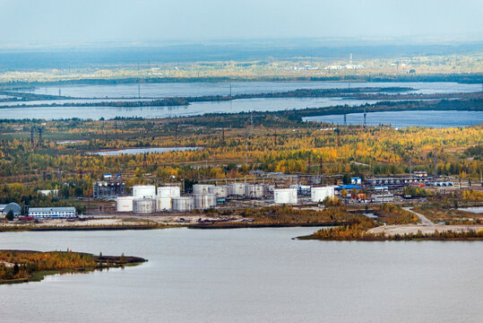 Aerial view of beautiful Lake Samotlor surrounded by industrial areas and forests in autumn, Tyumen Oblast, Russia.