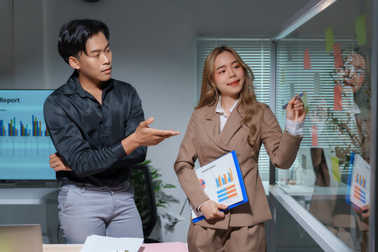 Asian businesswoman showing business analysis on transparent board to businessman in office meeting room