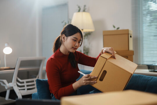 Woman labels a moving box carefully, preparing for her house move with focus and organization