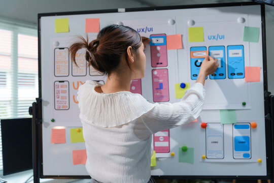 Uxui designer improving user experience on mobile app wireframe using whiteboard and colorful sticky notes in office