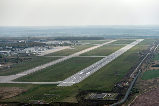 Aerial view of a busy airport with a runway and terminal surrounded by beautiful countryside, Kazan, Russia.