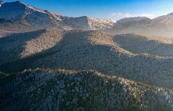 Aerial view of majestic Sayan Mountains covered in snow with serene forests, Khakassia Republic, Russia.
