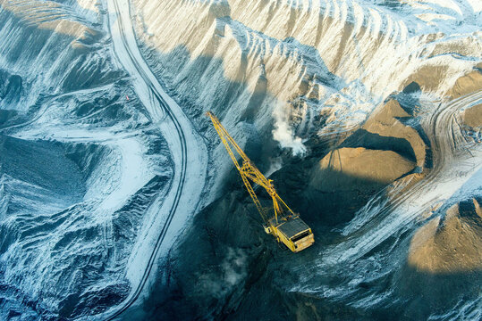 Aerial view of chernogorsky coal mining site with excavators and snow-covered terrain, Khakassia republic, Russia.