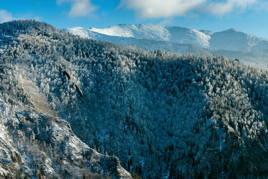 Aerial view of breathtaking Sayan Mountains covered in pristine snow and surrounded by tranquil forests, Khakassia Republic, Russia.