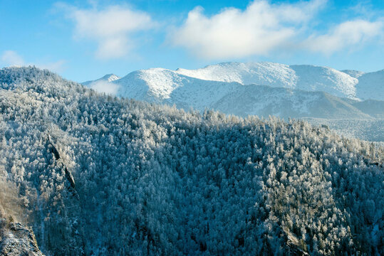 Aerial view of majestic Sayan Mountains covered in snow with serene forests and pristine wilderness, Khakassia Republic, Russia.