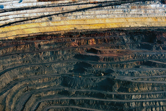 Aerial view of open pit mine with layers of terrain and heavy machinery, stary oskol, russia.