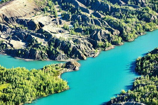 Aerial view of serene blue water lake surrounded by lush forest and majestic mountains, Tula oblast, Russia.