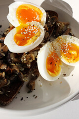 Closeup of Cut Soft Boiled Eggs on Bread Toast with Roasted Mushrooms. Breakfast, Brunch.