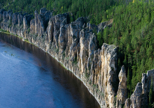 Aerial view of majestic Lena Pillars and serene river surrounded by unspoiled forest and rocky cliffs, Lena Pillars National Park, Russia.