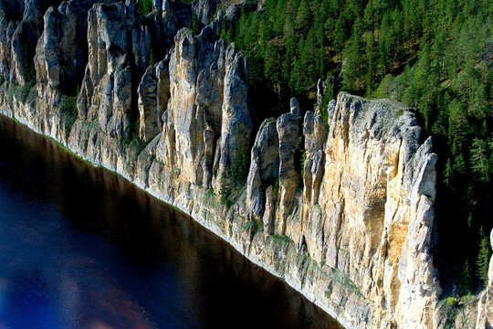 Aerial view of majestic lena pillars and rugged cliffs surrounded by serene forest and river, Lena Pillars National Park, Yakutia Republic, Russia.