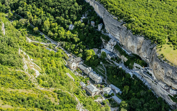Aerial view of assumption monastery of the caves surrounded by lush greenery and cliffs, Bakhchysarai Raion, Russia.