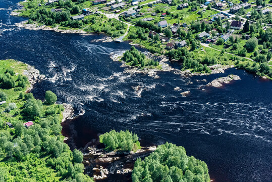 Aerial view of Onega Bay with serene river, lush forest, and quaint village, Republic of Karelia, Russia.