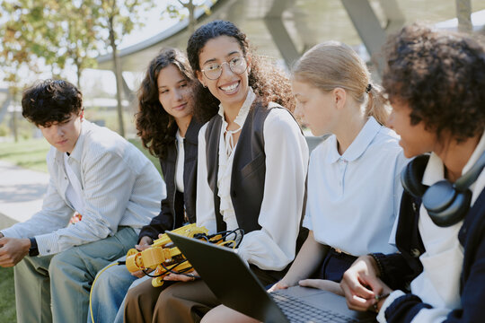 Young mixed race robotics teacher holding yellow robot while looking at her beloved multiracial students