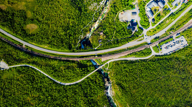 Aerial view of scenic canyon with train tracks and cars alongside the lush Abiskojakka River, Abisko National Park, Sweden.