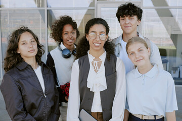 Medium close up of young smiling teacher and her beloved multiracial students