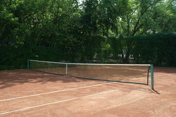 Fragment of an empty outdoor clay tennis court. Grid and marking lines visible. Sport game, Leisure activity.