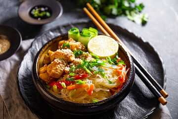 A bowl of glass or cellophane noodles with Asian caramelized chicken breast on a table