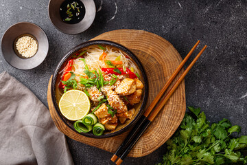 A bowl of glass or cellophane noodles with Asian caramelized chicken breast on dark grey background...